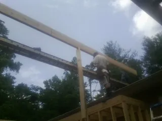 Carpenter setting a ridge beam over a new addition frame — Ice Dam Removal by Roofing Brothers in Olivet