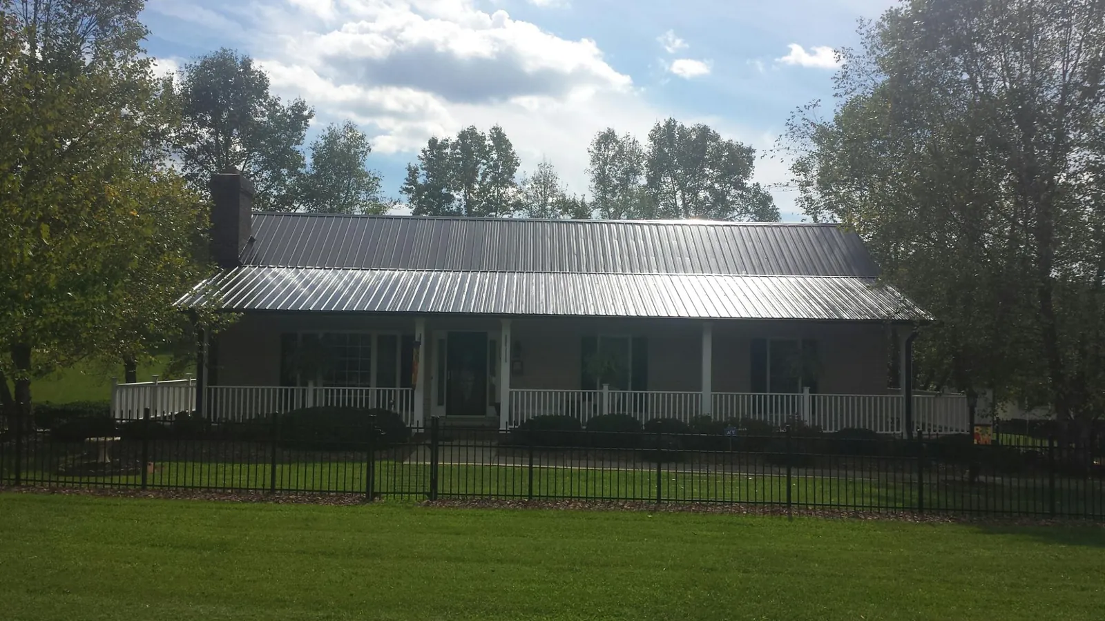 Gray metal roof on a brick ranch with a full width front porch — Gutter Guard Installation work by our crew in Olivet
